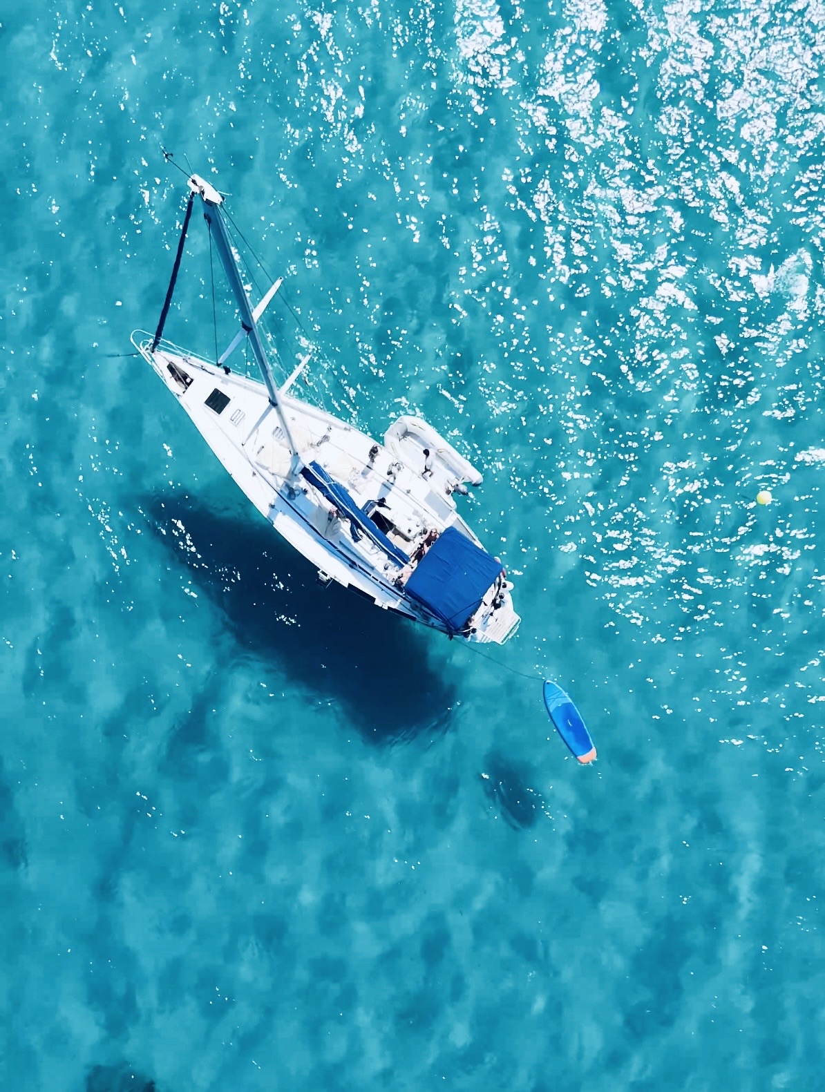 Aerial view of the sailboat and a paddleboard in clear turquoise water