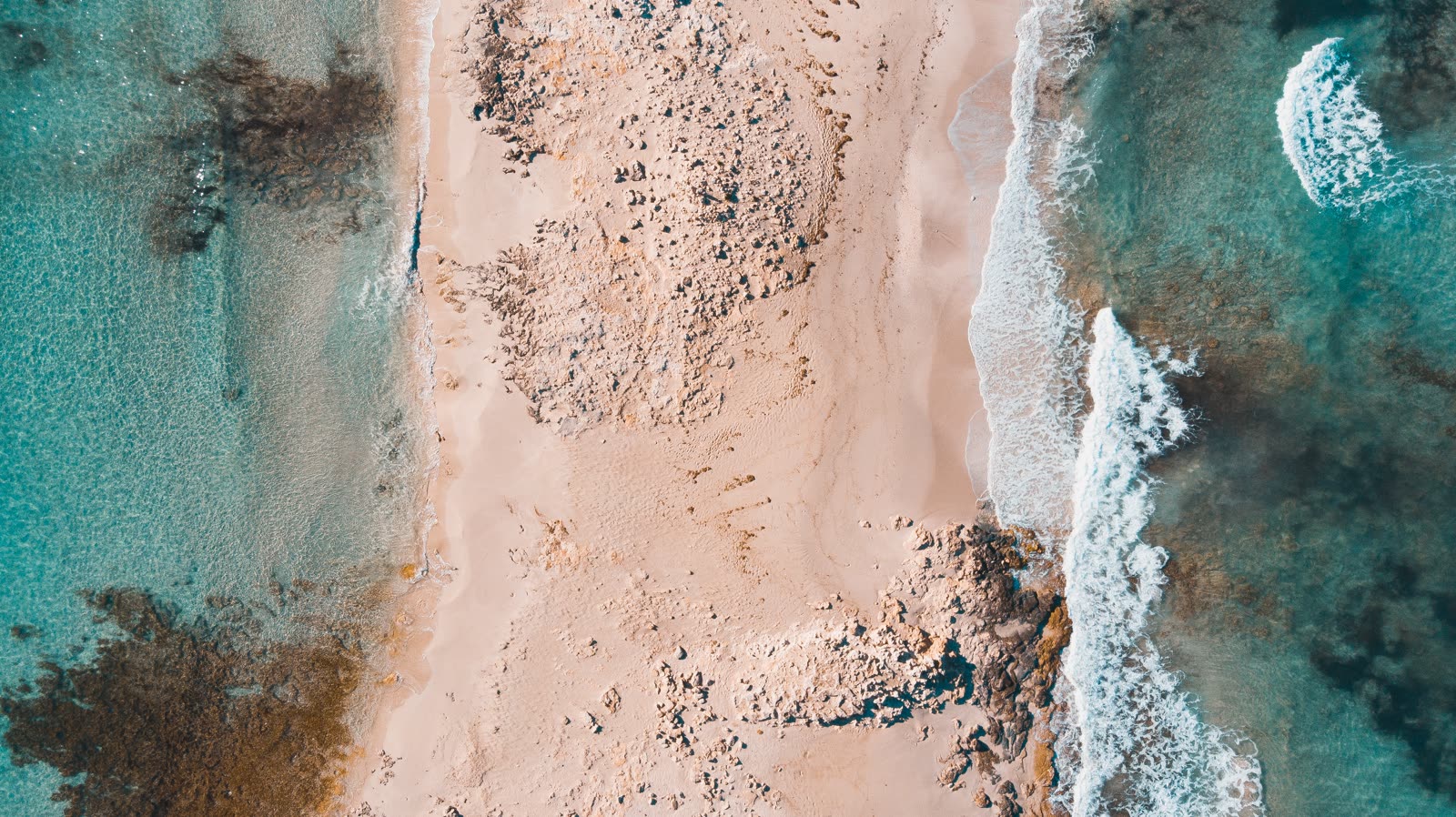Aerial view of sand, rock and clear water at Espalmador