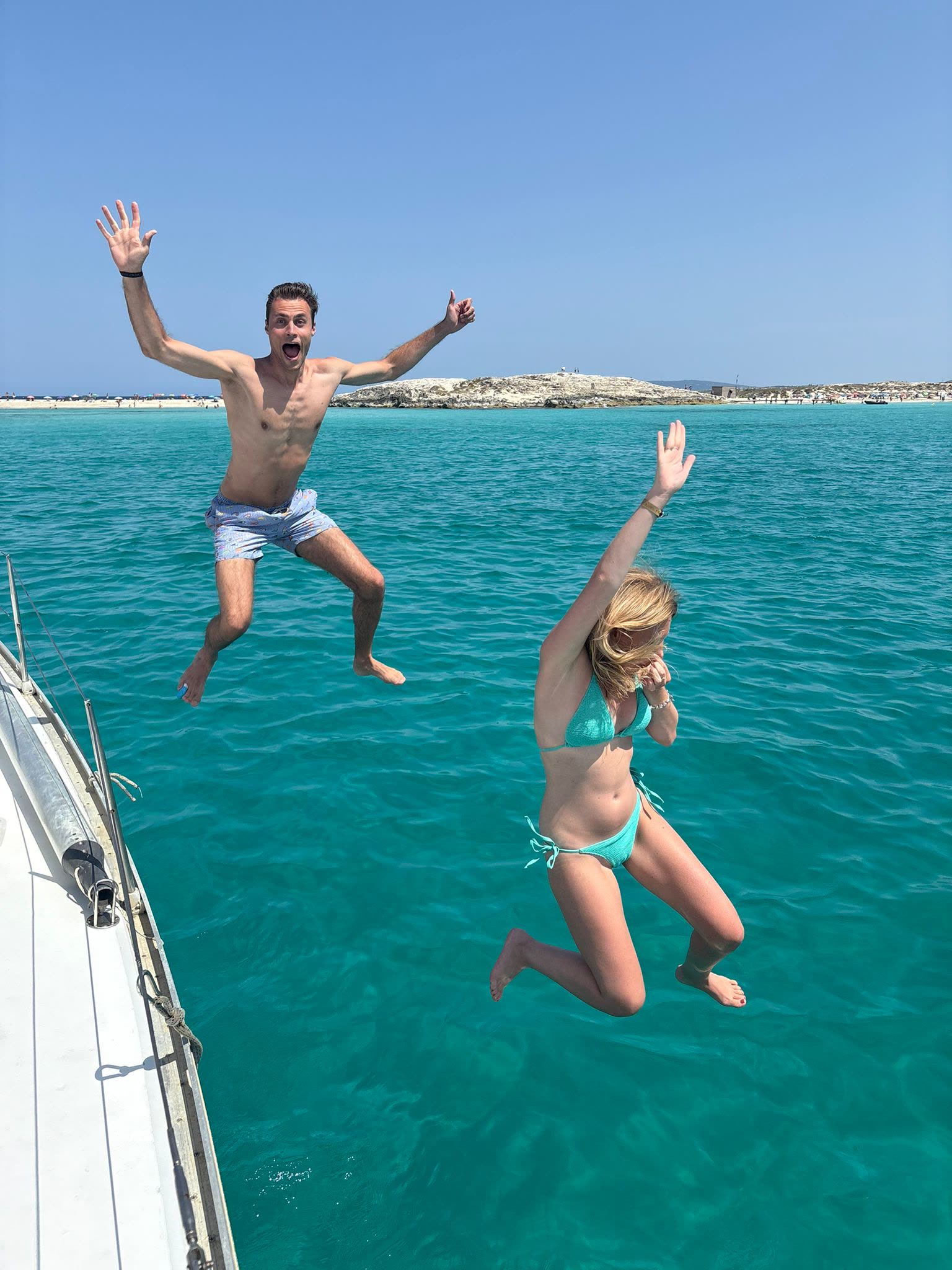 Guests jumping from a sailboat into turquoise water off Formentera